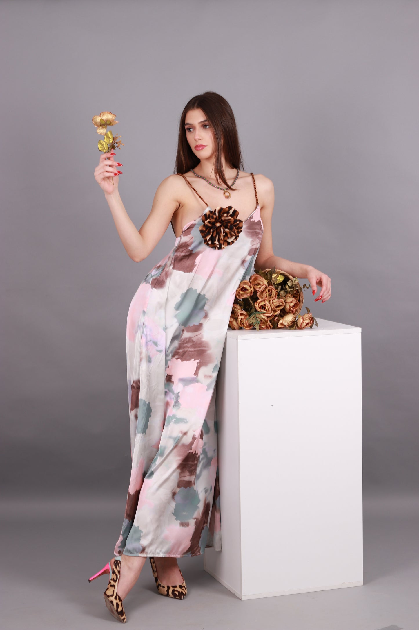 Woman in a long dress desert colors holding a golden flower and a basket of roses