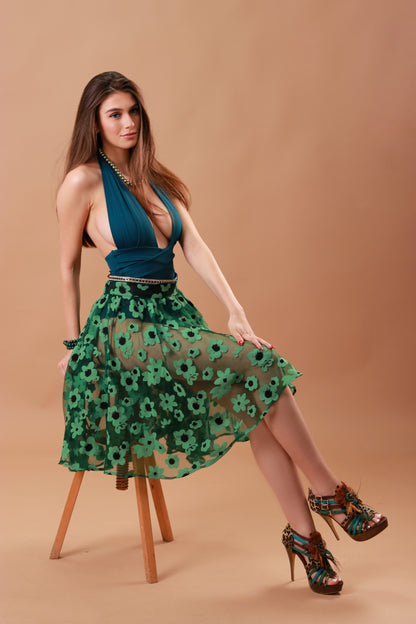 Model seating on a chair wearing the Lovran Love swimsuit in Jungle Green with the special treated skirt in Green Flowers by Paraima special collections